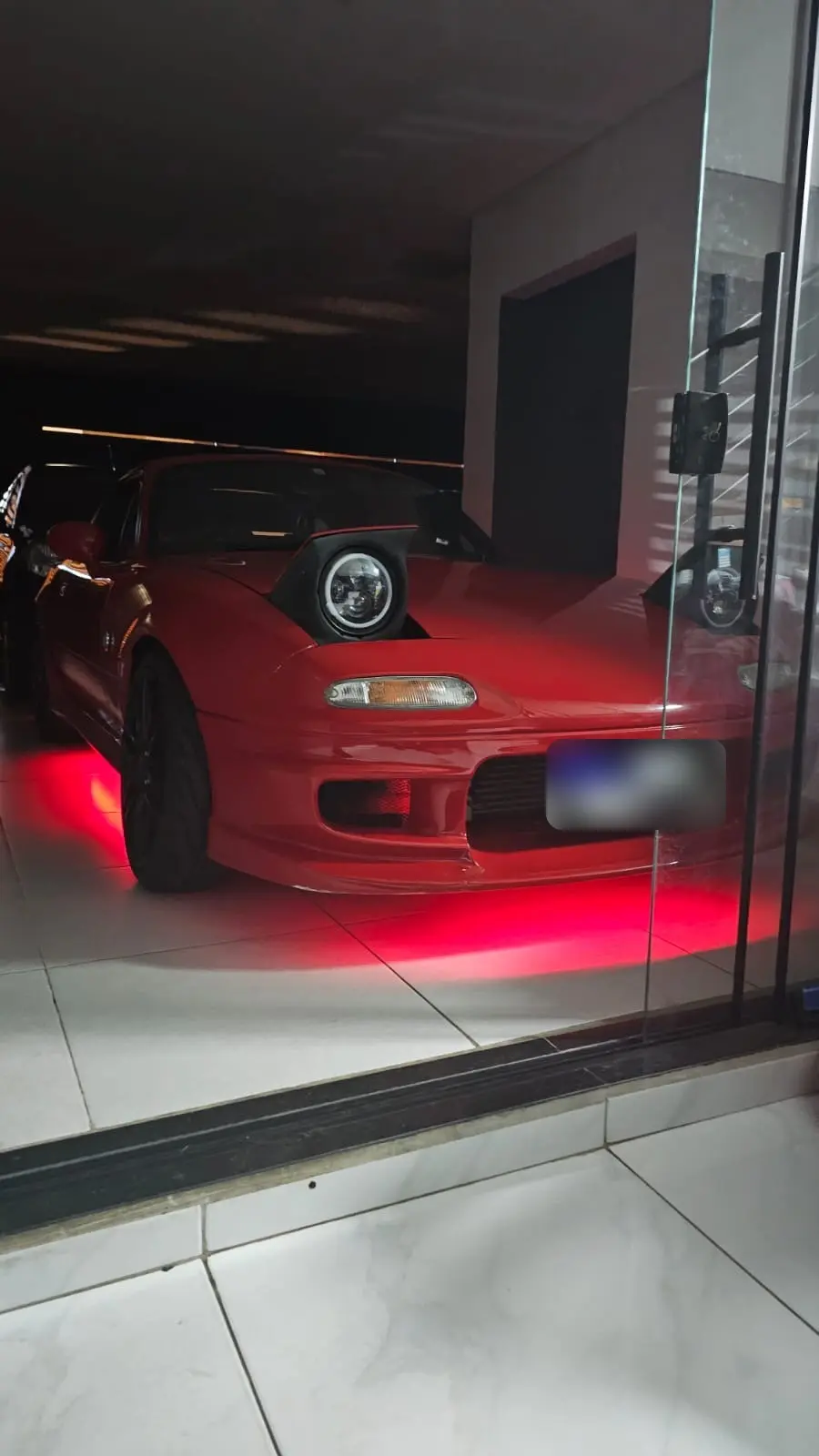 Mazda Miata vermelho com neon vermelho embaixo do carro e farol redondo de LED