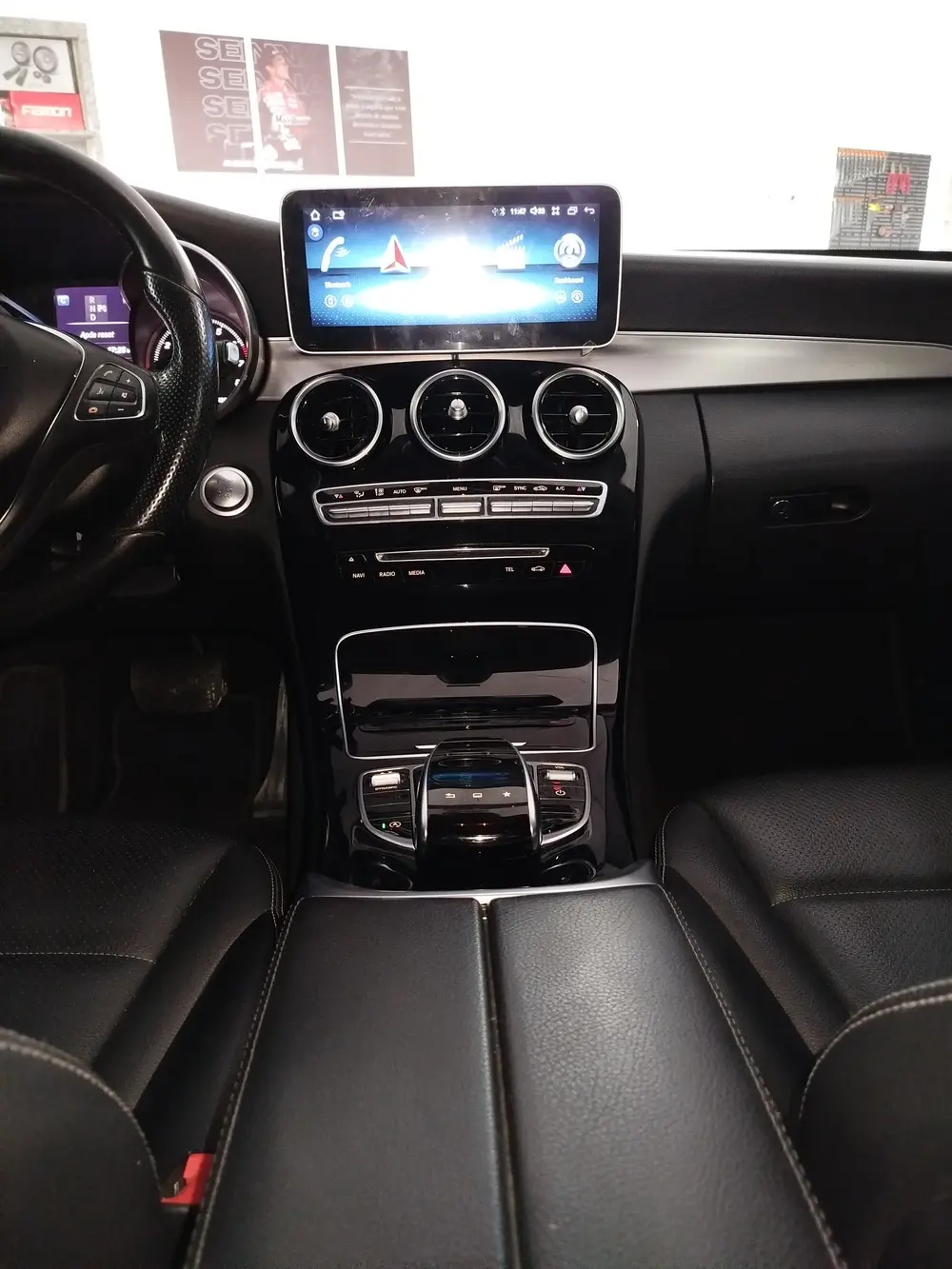 Painel de Mercedes-Benz Classe C com central multimídia, visto do banco de trás