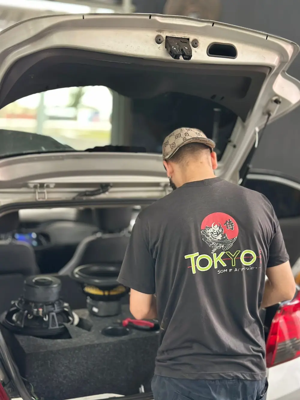 Jakson instalando caixa com subwoofers no porta-malas